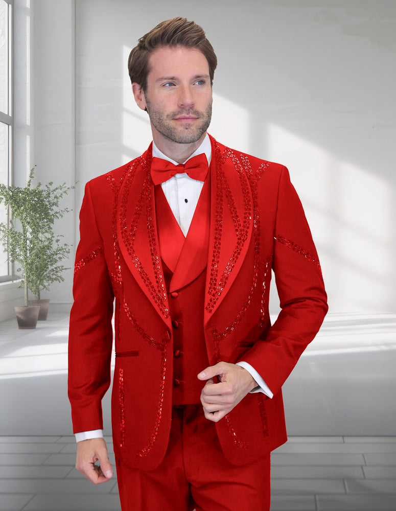 A man showcases the bold style of Statement Clothing's STATEMENT CLOTHING | CHIC-RED tuxedo, featuring bright red fabric with sequined detailing, a red bow tie, and white shirt in a well-lit room with large windows and a potted plant.