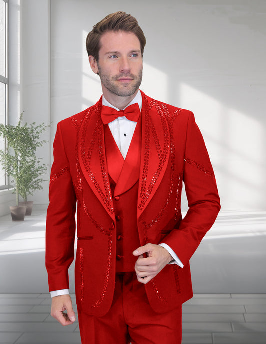 A man showcases the bold style of Statement Clothing's STATEMENT CLOTHING | CHIC-RED tuxedo, featuring bright red fabric with sequined detailing, a red bow tie, and white shirt in a well-lit room with large windows and a potted plant.