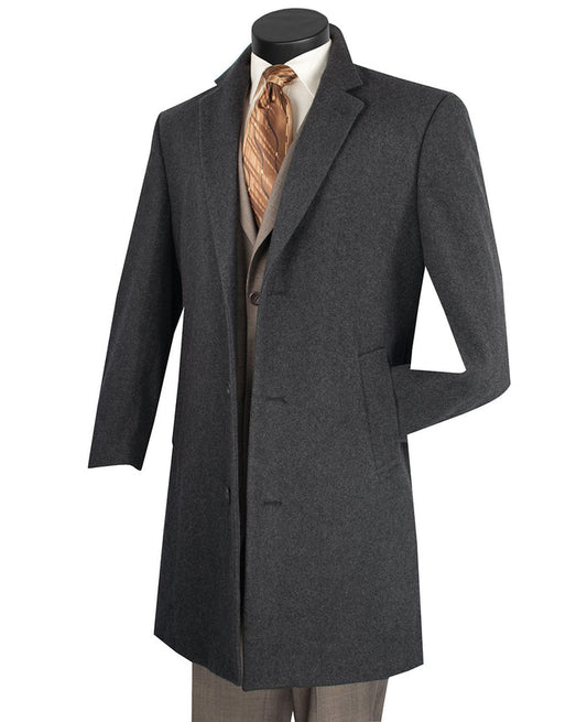 A charcoal CL38 top coat from Vinci Suits, crafted from 70% wool and 30% cashmere, elegantly drapes over a light brown suit with a crisp white shirt and gold patterned tie, exuding timeless sophistication.