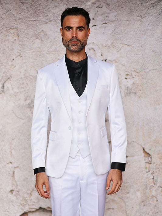 A man stands against a light-textured wall wearing the INSOMNIA CLASSICO 3PC Tailored Fit Satin Spandex White Suit by Insomnia, paired with a black dress shirt—ideal for a sophisticated night out.