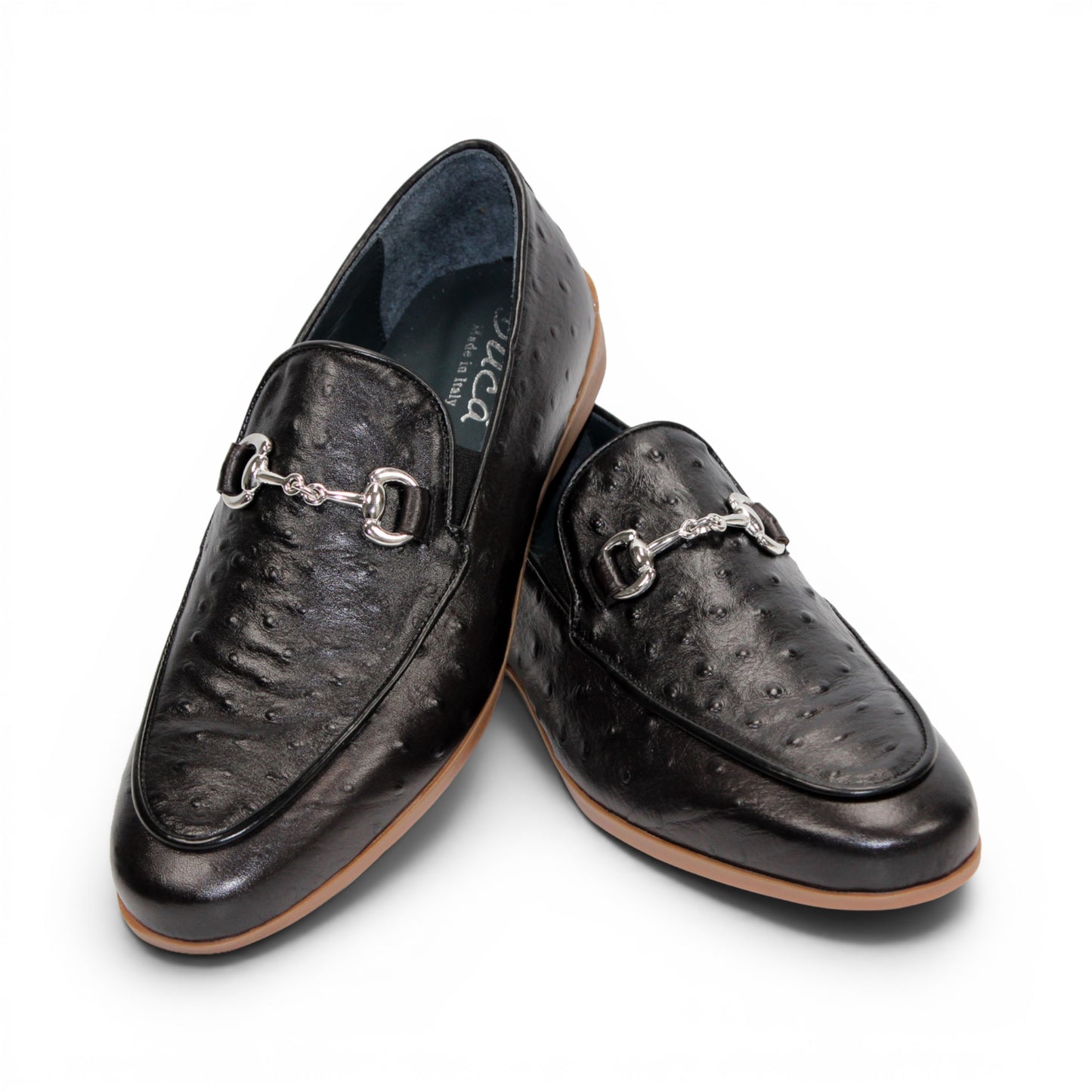 The Duca Cortona Black by Duca Di Matiste is a black Stampa Struzzo leather loafer, crafted in the style of a classic Italian shoe, featuring a silver buckle detail and a light brown rubber sole. Shown in profile on a white background, this refined design is an excellent choice for luxury footwear enthusiasts.