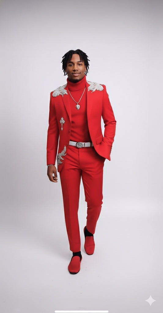 Model wears the Unique Design Menswear Custom Prom Suit Red with Clear Rhinestones, paired with a red turtleneck, red loafers, and a silver necklace, standing against a plain light background.