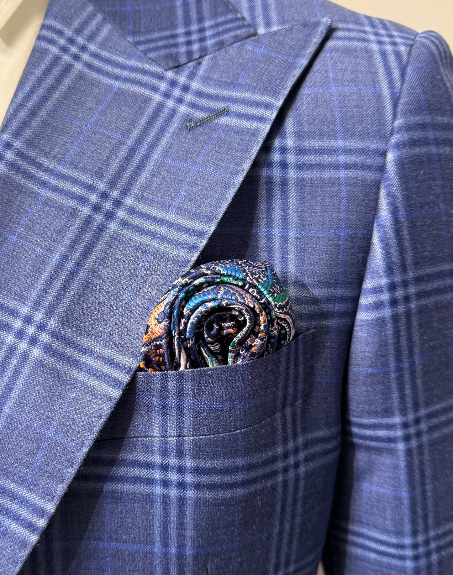 An older man in a Tiglio Rosso Orvietto Blue Plaid Semi Wide Leg suit (TL5074) with matching vest, white shirt, paisley tie, and pocket square stands against a plain white background.