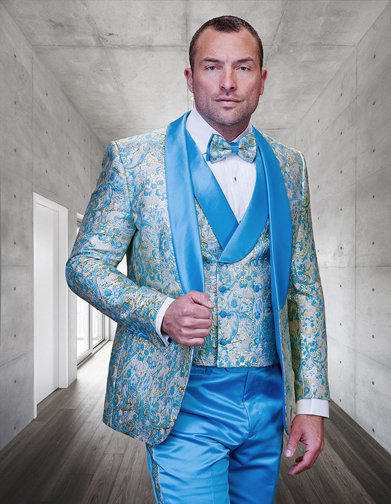 A man wears the STATEMENT CLOTHING | DELANO-2-TURQUOISE tuxedo by Statement Clothing, featuring a modern fit and matching bowtie, as he stands in a sleek concrete hallway with wood flooring.