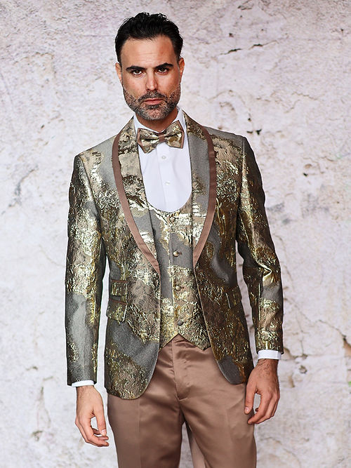 A man in an Insomnia MANZINI DELMAS 3-Piece Slim Fit Shiny Metallic Pattern Taupe Tuxedo with a bow tie stands against a textured wall.