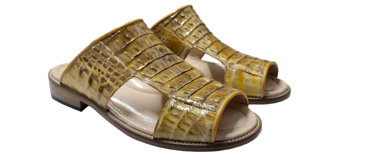 The Fennix Diego Yellow slide sandal by Fennix of Italy features yellow crocodile-embossed leather, an open toe, a wide strap, and a flat wooden sole—an eye-catching piece of exotic footwear inspired by Italian-made luxury shoes, shown from the side against a white background.