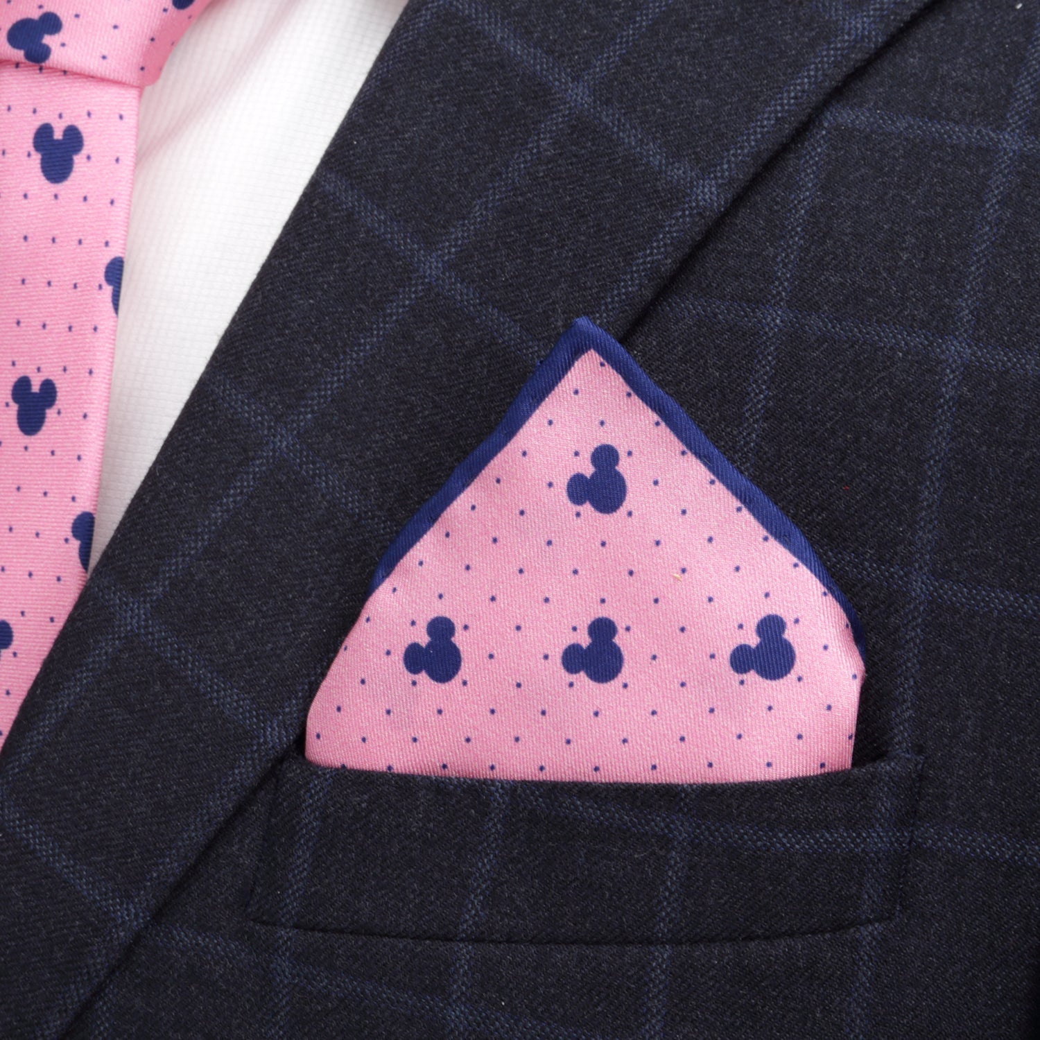 The Disney Mickey Mouse Dot Pink Pocket Square by Cufflinks.com features navy Mickey Mouse silhouettes and dots on pink silk, bordered in navy blue—a stylish Disney accessory.