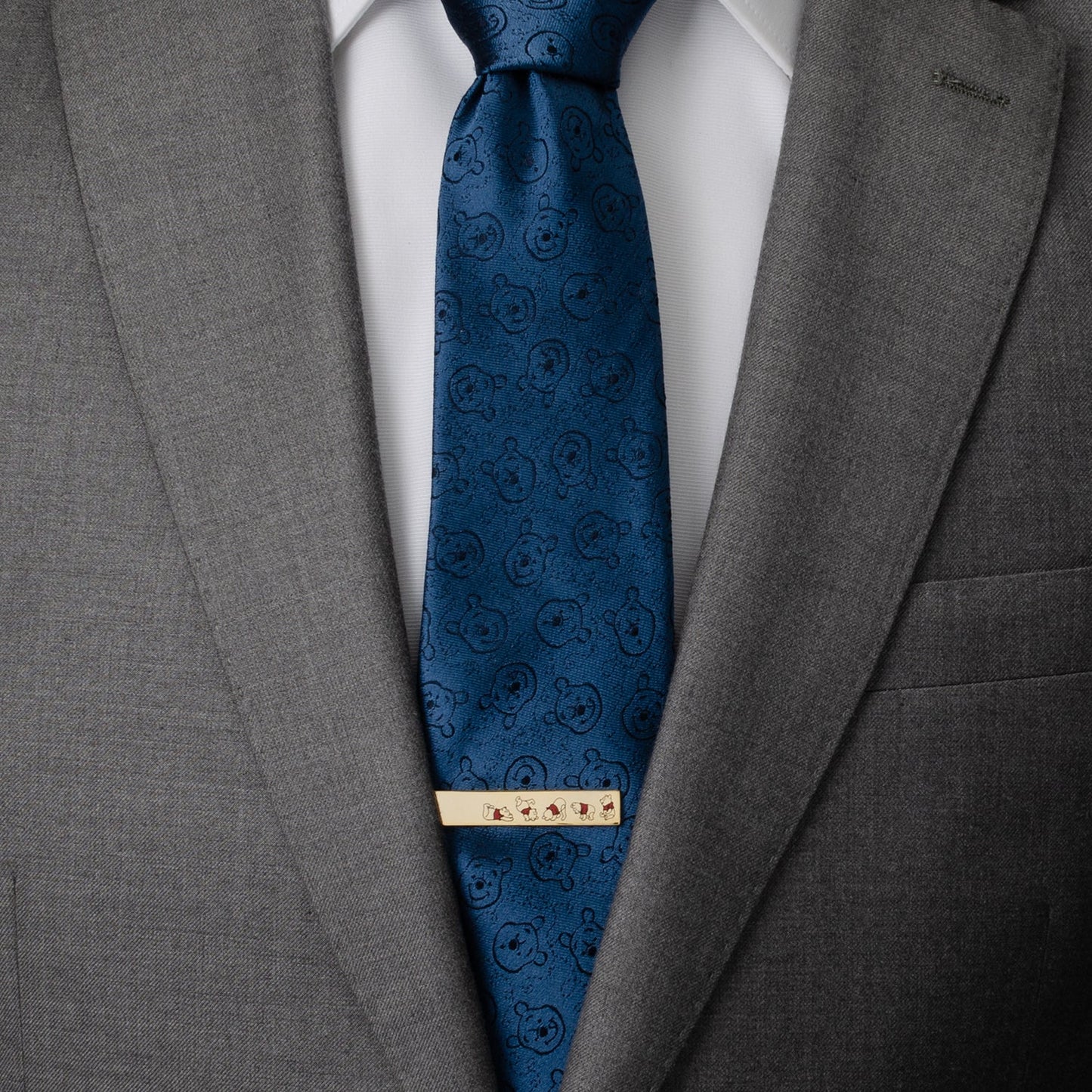 The Disney Winnie the Pooh Hidden Message Tie Bar by Cufflinks.com features gold designs: one displays Winnie the Pooh in multiple poses, the other is engraved with "OH BOTHER." A perfect accessory for classic Winnie the Pooh fans.