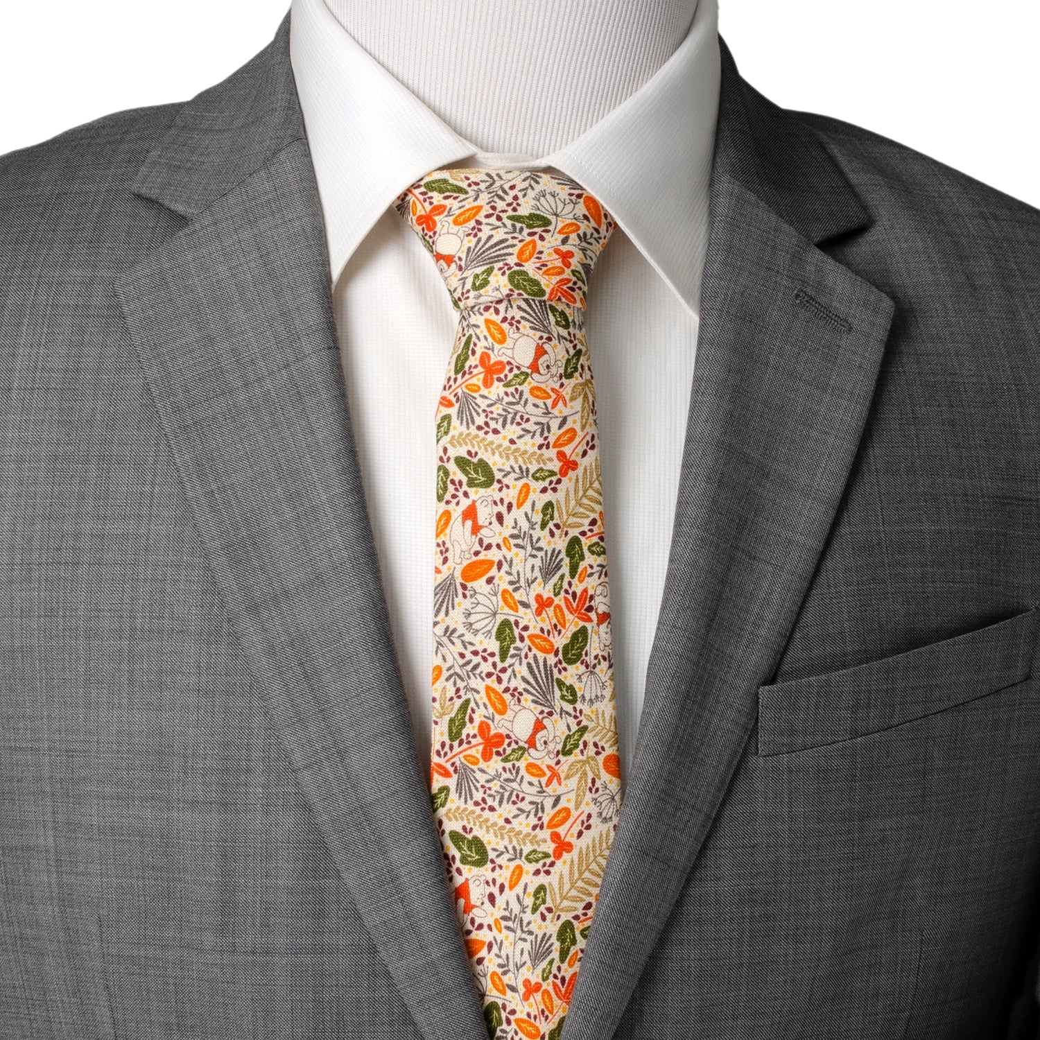 The Disney Winnie the Pooh Tan Patterned Men's Tie by Cufflinks.com features a beige background with autumn leaves in orange, yellow, green, and brown, plus subtle animal illustrations.