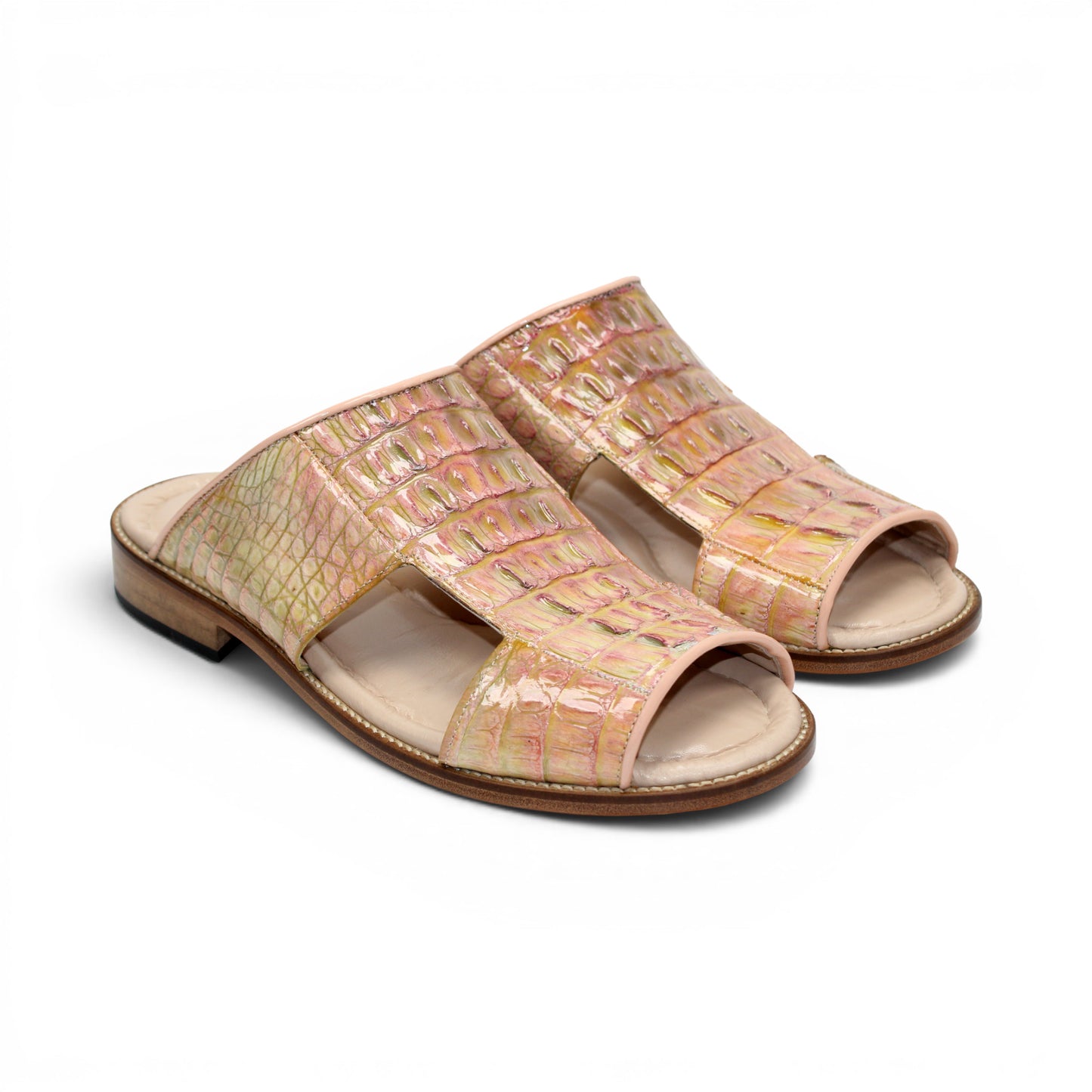 The Fennix Diego Pink by Fennix of Italy is a flat open-toe sandal crafted from genuine alligator leather in a striking pink and yellow crocodile pattern, featuring cut-out details and a low wooden heel for an exotic touch of luxury, shown in profile against a white background.