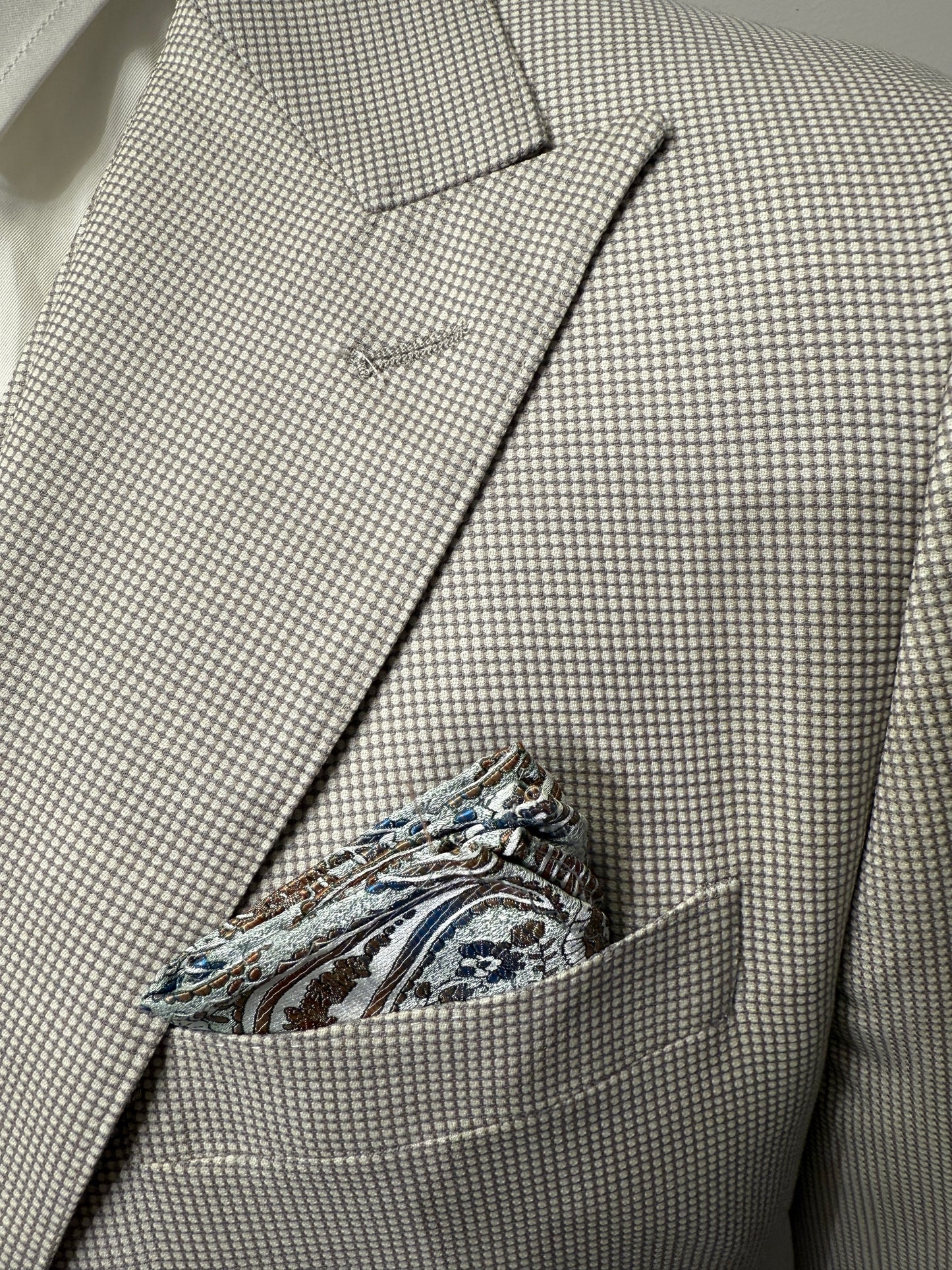 An older man with gray hair and beard models the Tiglio Luxe Prosecco Light Taupe Birdseye Modern Fit TL4128 suit by Tiglio Luxe, standing against a plain light background—showcasing refined, modern men's tailoring.