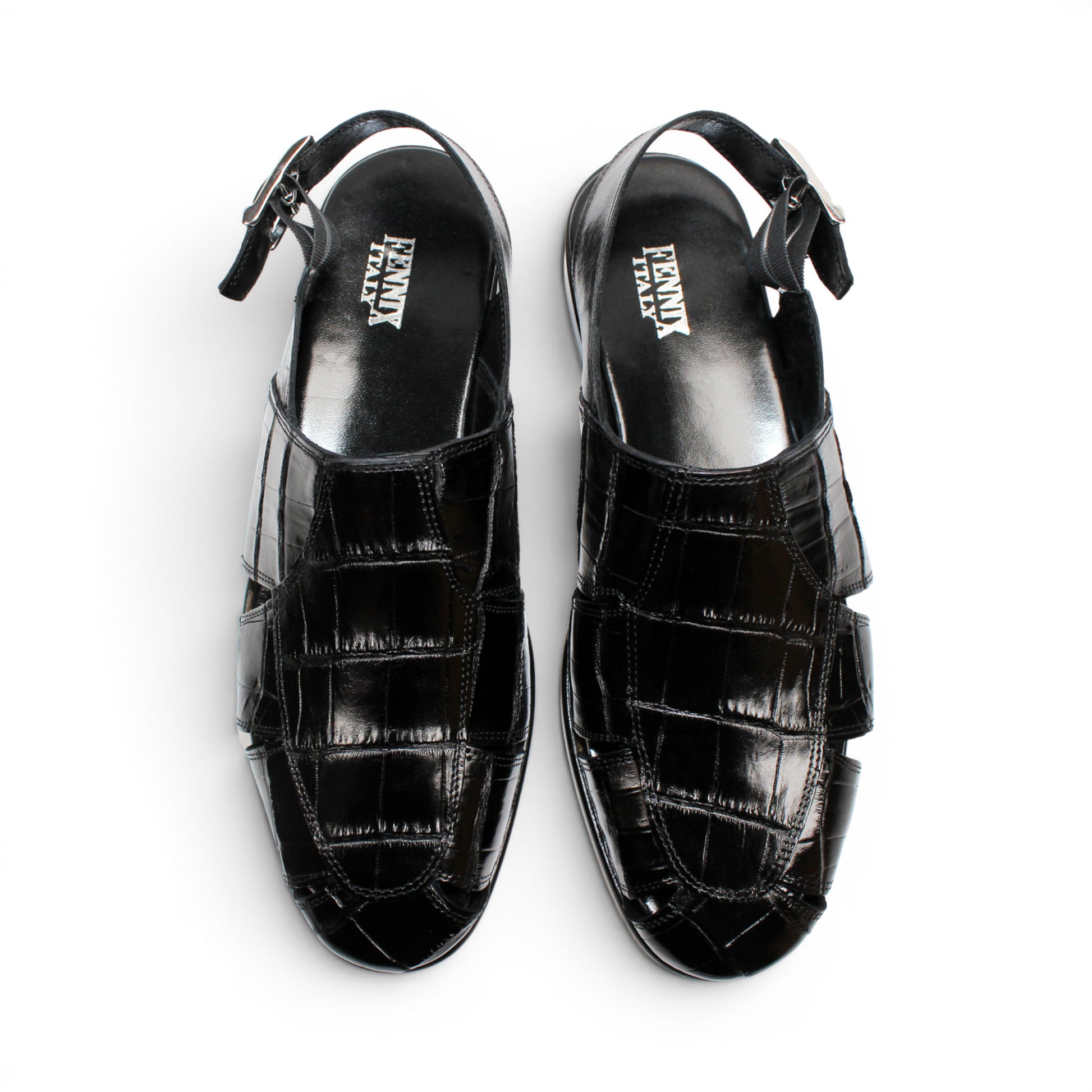 Introducing the Fennix F131 Black sandal by Fennix of Italy—a black leather design featuring a closed toe, open heel, silver buckle strap, and a flat sole, elegantly displayed on a white background. Crafted for those who value luxury footwear, this sandal offers refined style and comfort with every step.