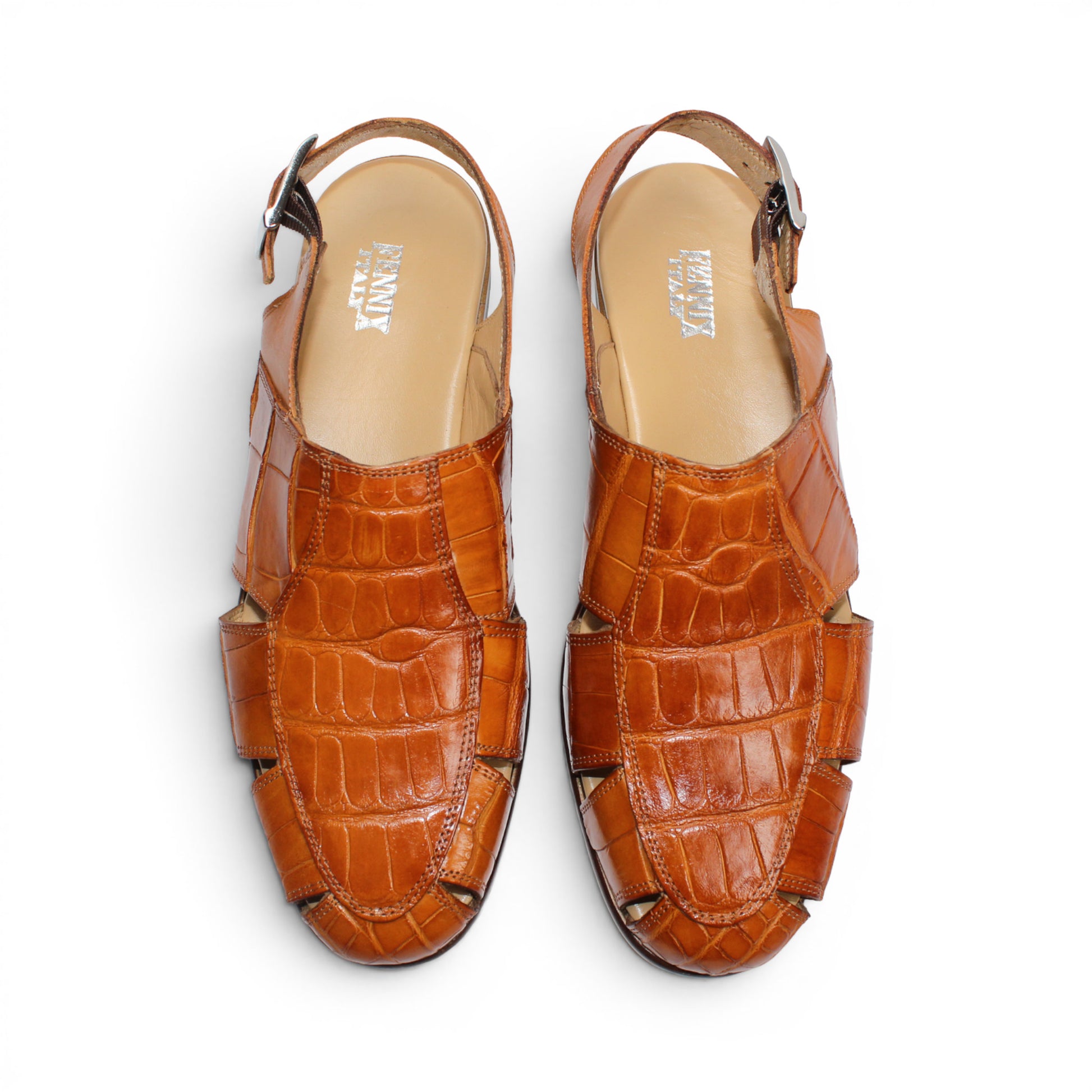The Fennix F131 Cognac sandal by Fennix of Italy is an open-toe design crafted from genuine alligator leather in a rich brown hue, featuring elegant cut-outs, a slingback strap with side buckle, and a low flat heel—perfect for those who appreciate true luxury footwear. Displayed on a white background.