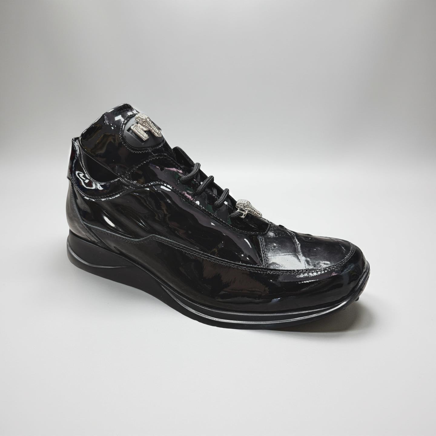 A close-up of the Mauri 8900/2 Patent Leather Baby Croc Shoes in black, featuring a glossy baby crocodile pattern and thick sole, displayed on a speckled floor with a brick wall background.