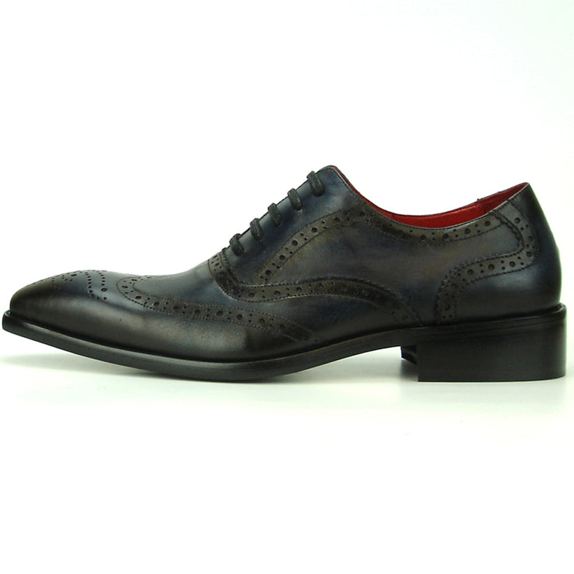 The FI-8710 Black Wing Tip Encore by Fiesso, a men’s fashion shoe in black and navy blue crafted from leather with decorative perforations, black laces, and a low heel, is displayed on a white background.
