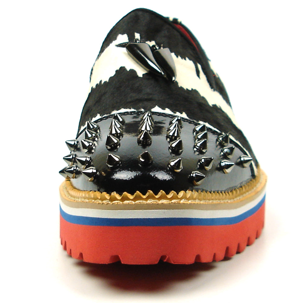 The FI-7455 Black White Cap Toe Spikes Slip On with Tassel by Fiesso features handcrafted leather, a red sole, blue trim, metal studs on the toe, and bold triangular metal accents—perfect for standout men’s fashion.