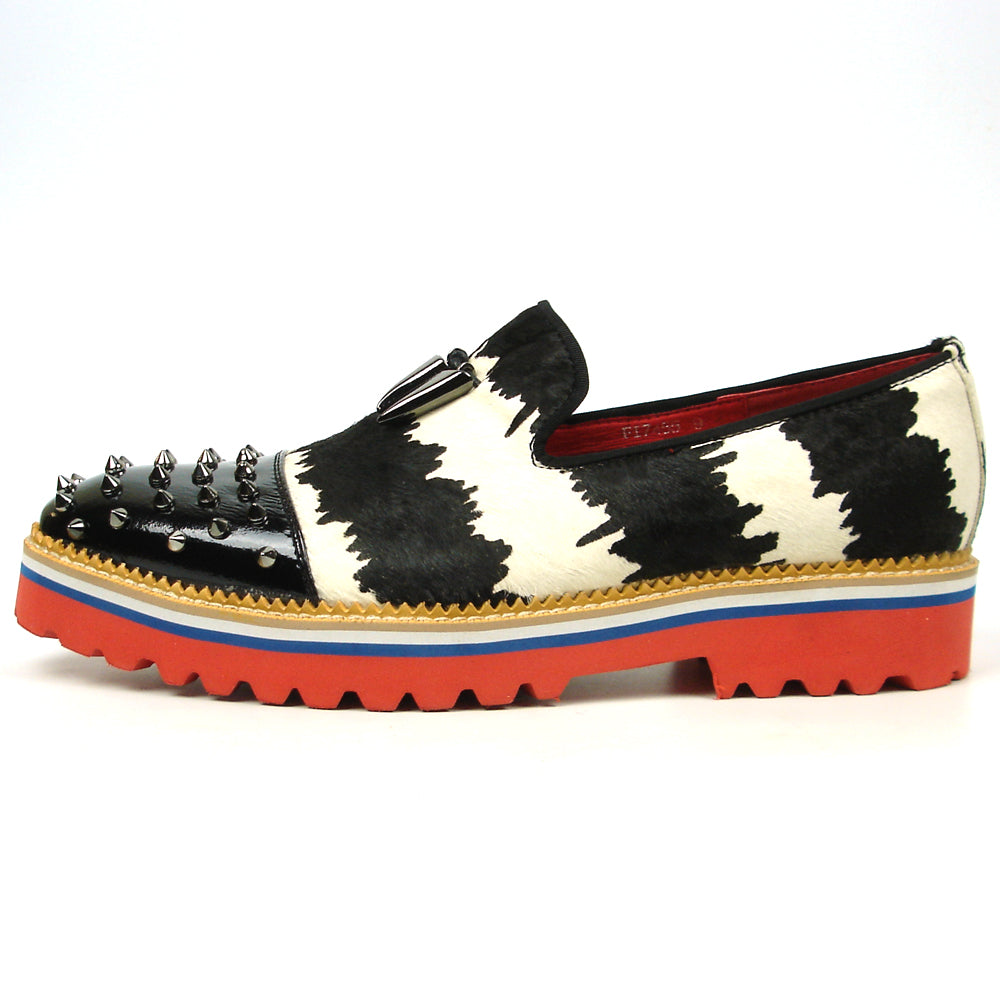 The FI-7455 Black White Cap Toe Spikes Slip On with Tassel by Fiesso features handcrafted leather, a red sole, blue trim, metal studs on the toe, and bold triangular metal accents—perfect for standout men’s fashion.