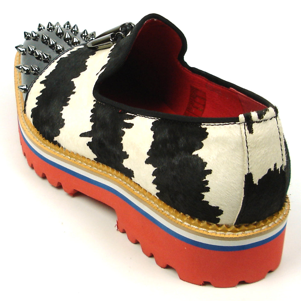The FI-7455 Black White Cap Toe Spikes Slip On with Tassel by Fiesso features handcrafted leather, a red sole, blue trim, metal studs on the toe, and bold triangular metal accents—perfect for standout men’s fashion.