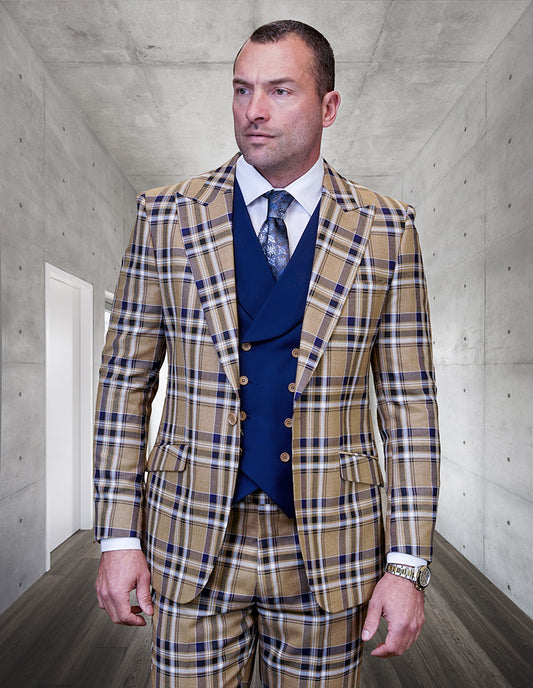 A man in the Statement Clothing FIRENZE-CAMEL Italian wool plaid suit with a navy vest and tie stands in a modern concrete hallway, looking slightly to the side.
