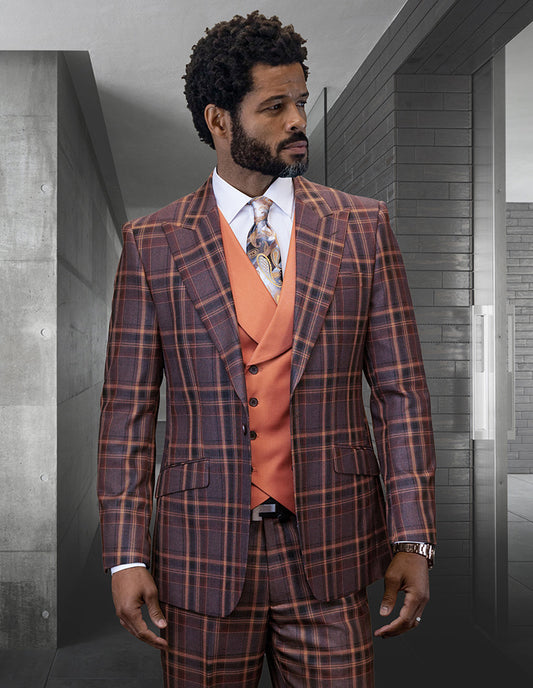A man in the STATEMENT CLOTHING | FIRENZE-COPPER suit by Statement Clothing—modern fit brown and orange Italian wool plaid with an orange vest, white shirt, and patterned tie—stands indoors against a modern backdrop.