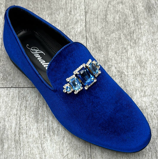The Exclusive Formal Dress Shoe Blue TIAGO by UNIQUE DESIGN MENSWEAR, crafted from genuine leather in Italy, showcases a blue velvet design adorned with three large blue gemstones surrounded by smaller clear stones, all set against a gray tiled floor.