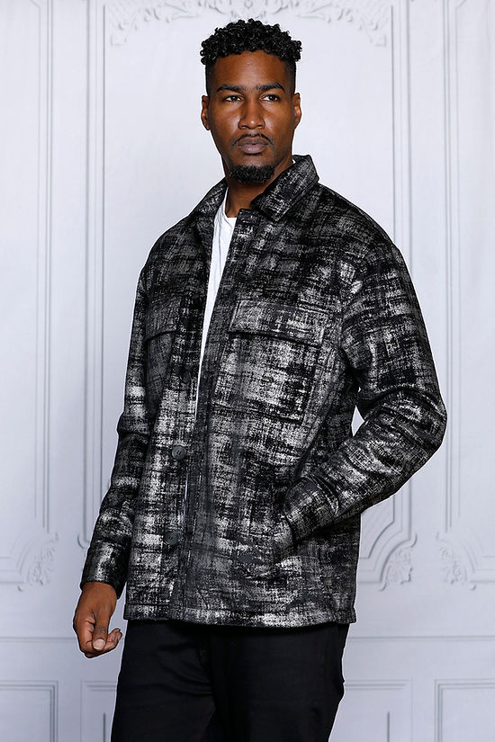 A man models the Insomnia's MANZINI GREECE Silver Metallic Fabric Button Down Coat, gazing to the side against an ornate white wall background.