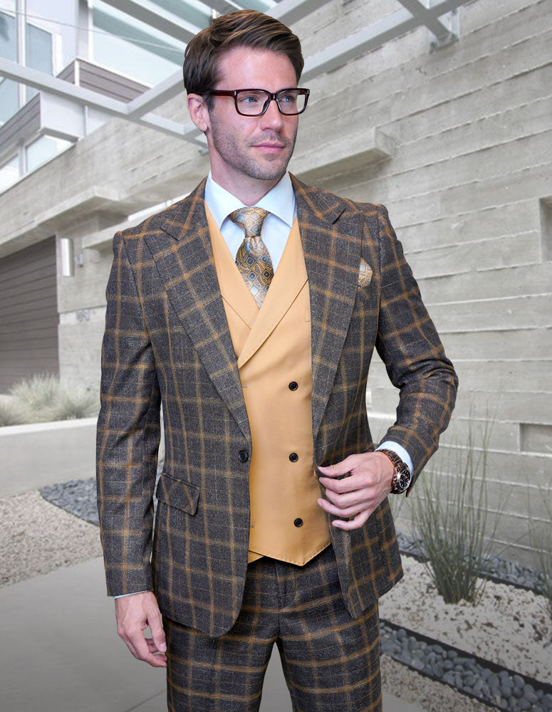 A man in glasses wears the STATEMENT CLOTHING | HARTFORD-CAMEL Italian Super 200's Wool Suit by Statement Clothing, paired with a mustard yellow vest and tie, standing outside a modern concrete building.