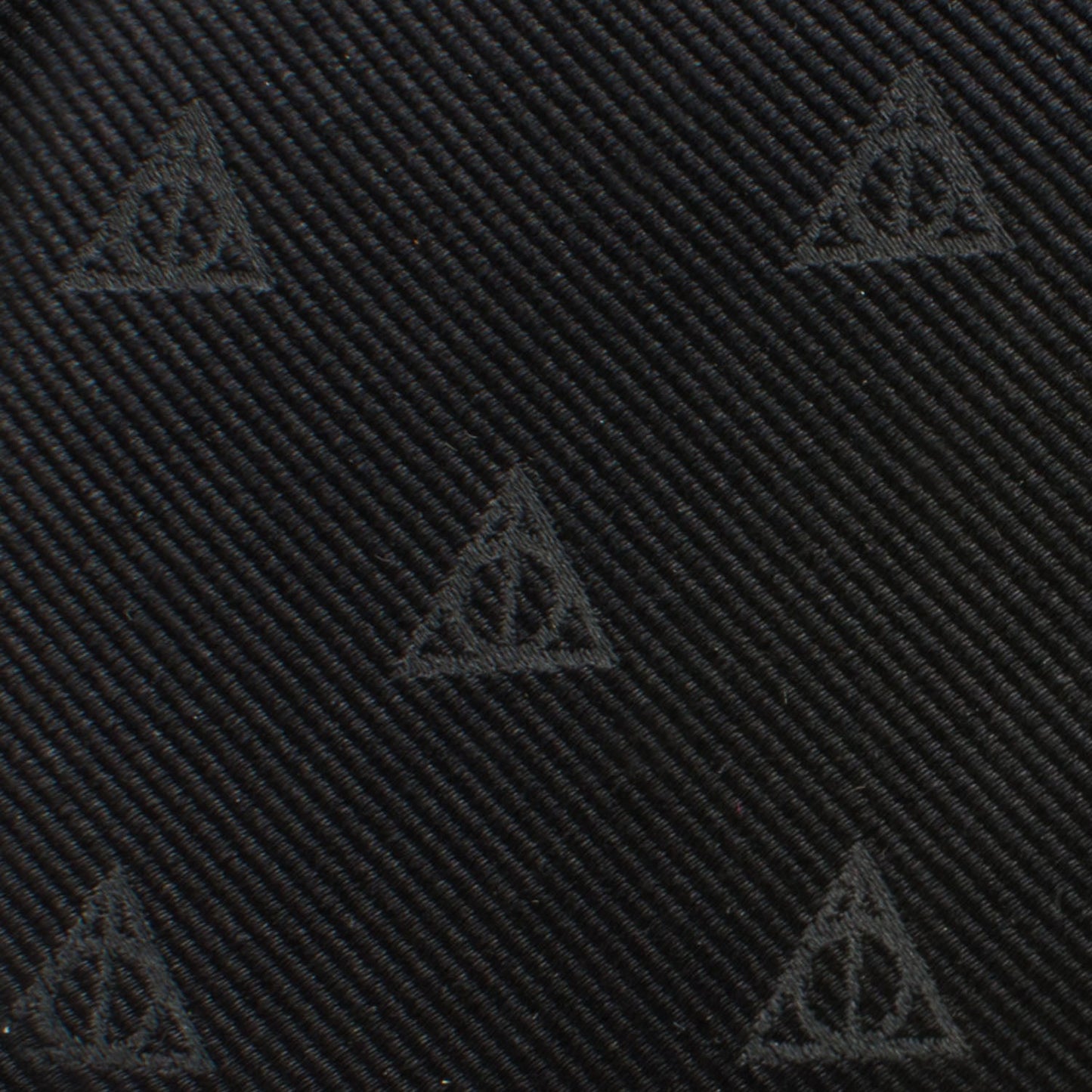 The Harry Potter Deathly Hallows Tie by Cufflinks.com is a black silk tie with a subtle, repeating pattern of small triangle symbols.