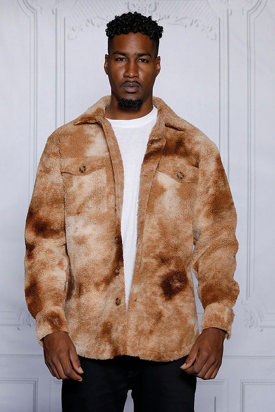 A man in a MANZINI ICELAND Brown Soft Fleece Button Sweater Shirt by Insomnia stands against a light gray background, accentuating his style with the crisp white t-shirt beneath.