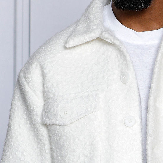 A man, exuding casual sophistication, stands against a light grey decorative wall wearing an Insomnia MANZINI ICELAND White Soft Fleece Button Sweater Shirt.