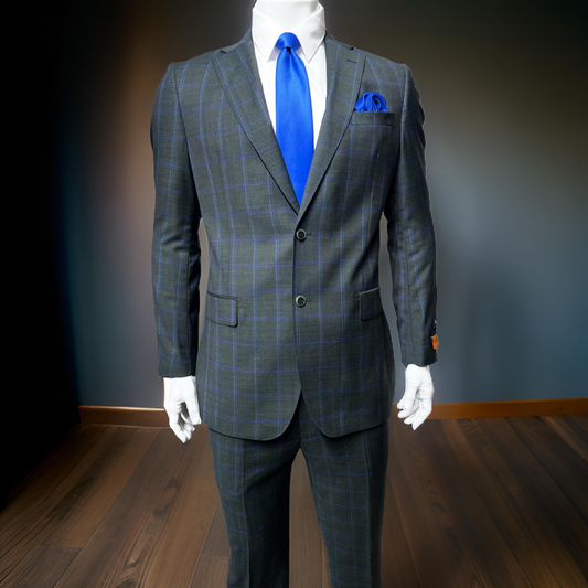 A mannequin showcases the Tiglio Luxe Dolcetto Modern Fit Suit TL3112 (52L ONLY)—a gray plaid men's Italian suit by Tiglio Luxe—with a blue tie and matching pocket square, standing on a wooden floor against a dark background.