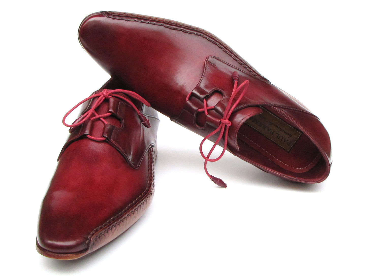 A pair of Paul Parkman Ghillie Lacing Handsewn Shoes in burgundy (022-BUR), featuring red laces, is displayed overlapping on a white background.