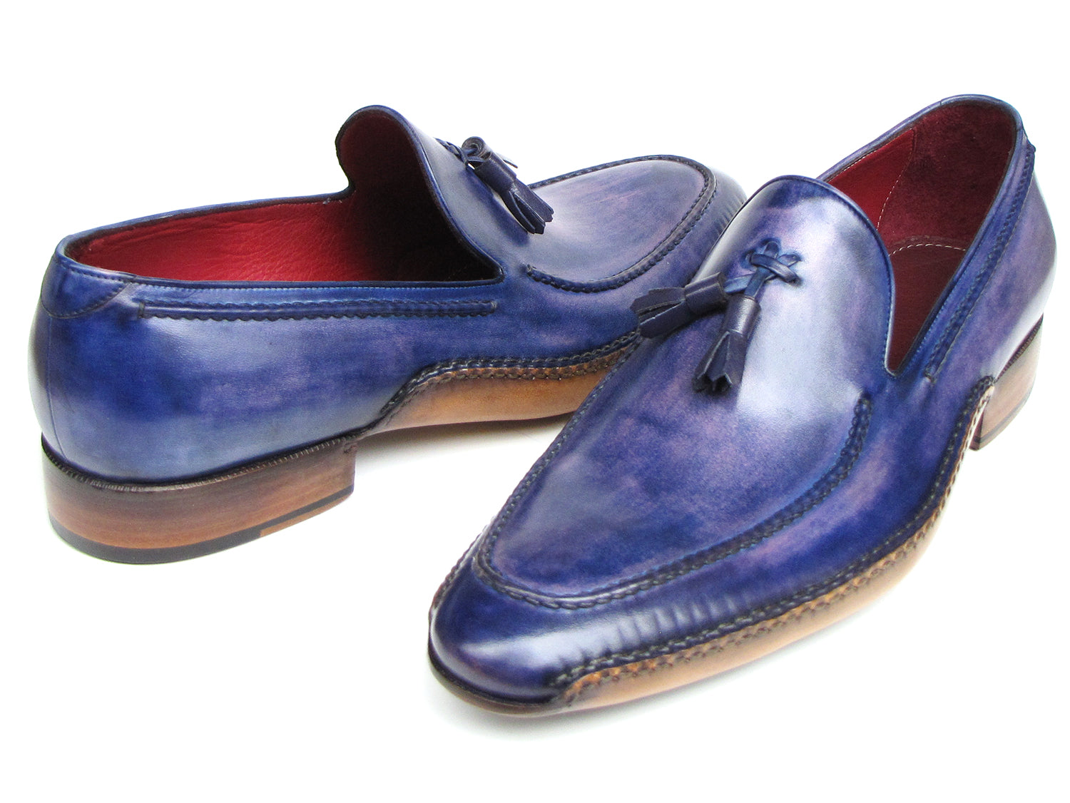 The Paul Parkman Side Handsewn Tassel Loafer Blue & Purple (082-BLU-PURP) pairs hand-painted blue and purple leather with a red interior lining and tan soles, offering stylish slip-on elegance for men.