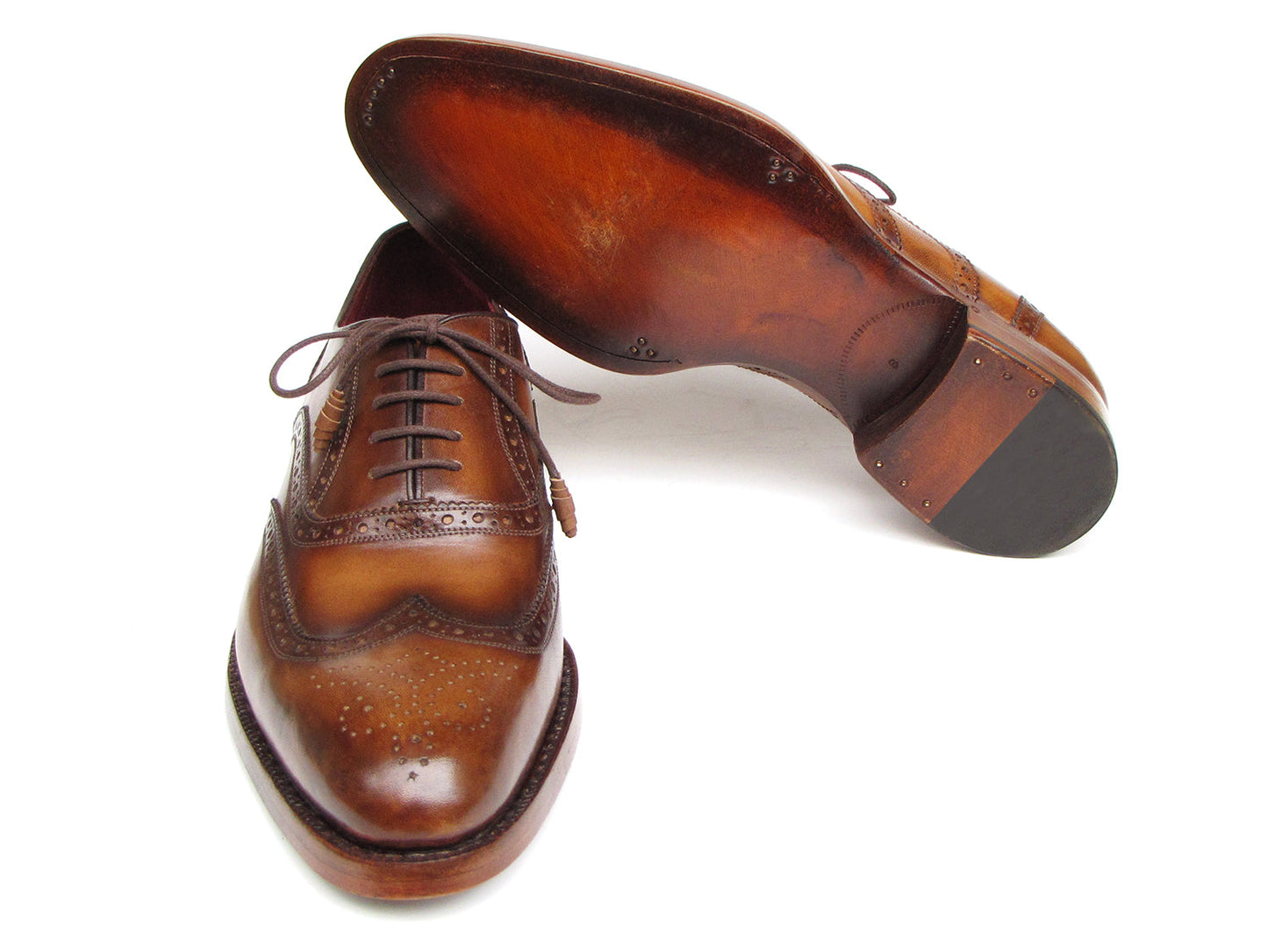 The Paul Parkman Wingtip Oxford Goodyear Welted Tobacco - 027-TAB shoes by Paul Parkman are exquisite handmade brown leather brogues that boast intricate designs and feature laces with Goodyear welted construction. Their elegant wooden soles enhance their appeal, beautifully displayed on a white background.