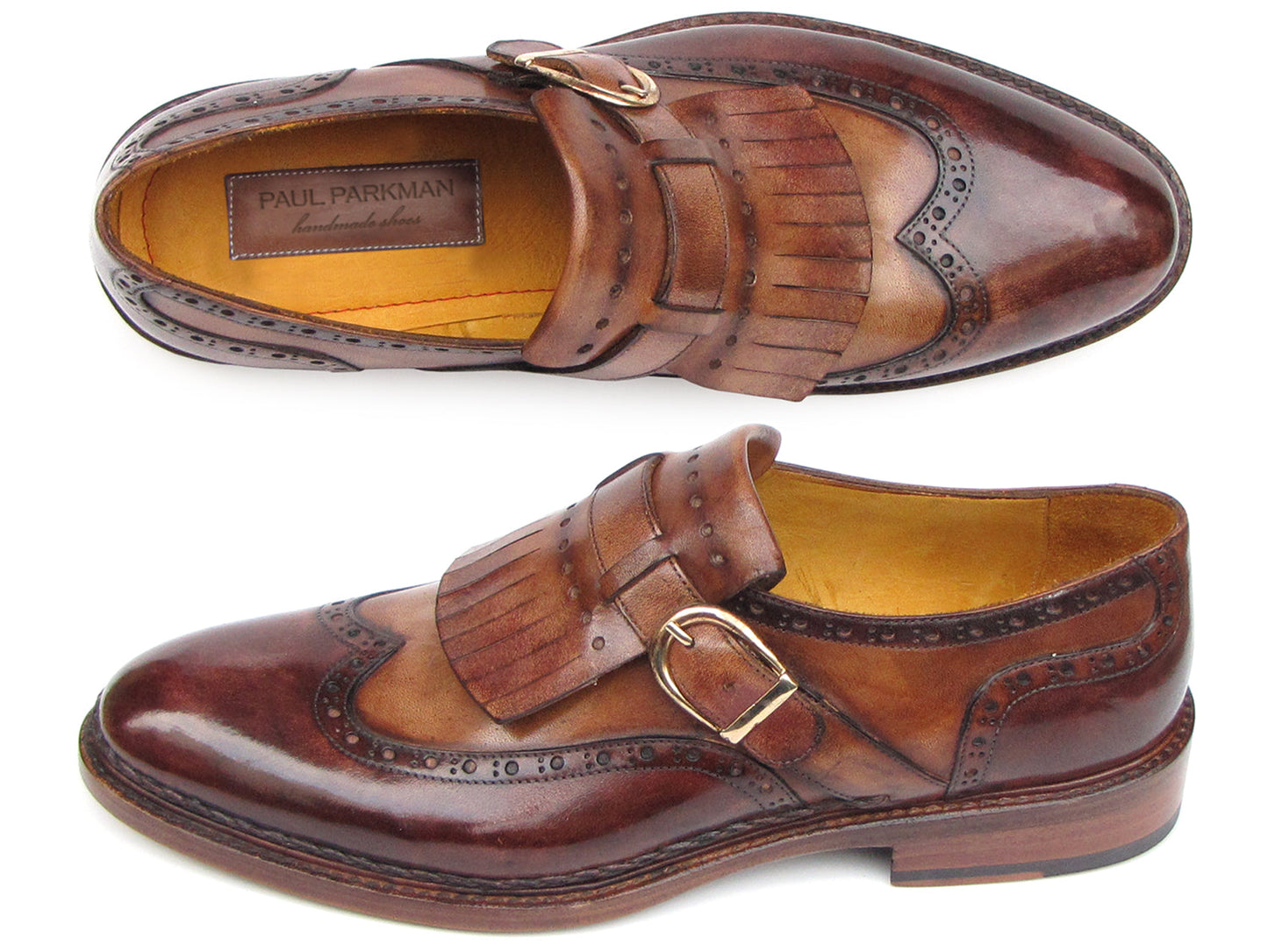 The Paul Parkman Wingtip Monkstraps Brown - 060-BRW features brown leather, decorative perforations, and a fringed kiltie detail. Handcrafted with Goodyear welted construction, this men's dress shoe is shown at a slight angle.