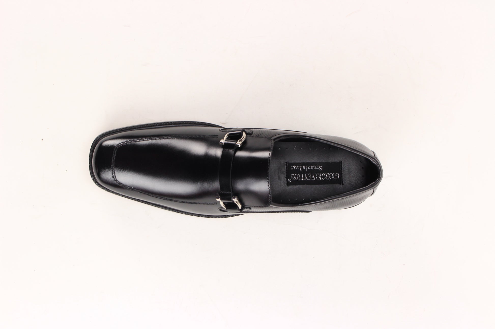 The Giorgio Venturi 7061 Black Leather Shoes feature smooth black leather, a silver buckle, low heel, and square toe, displayed against a white background.