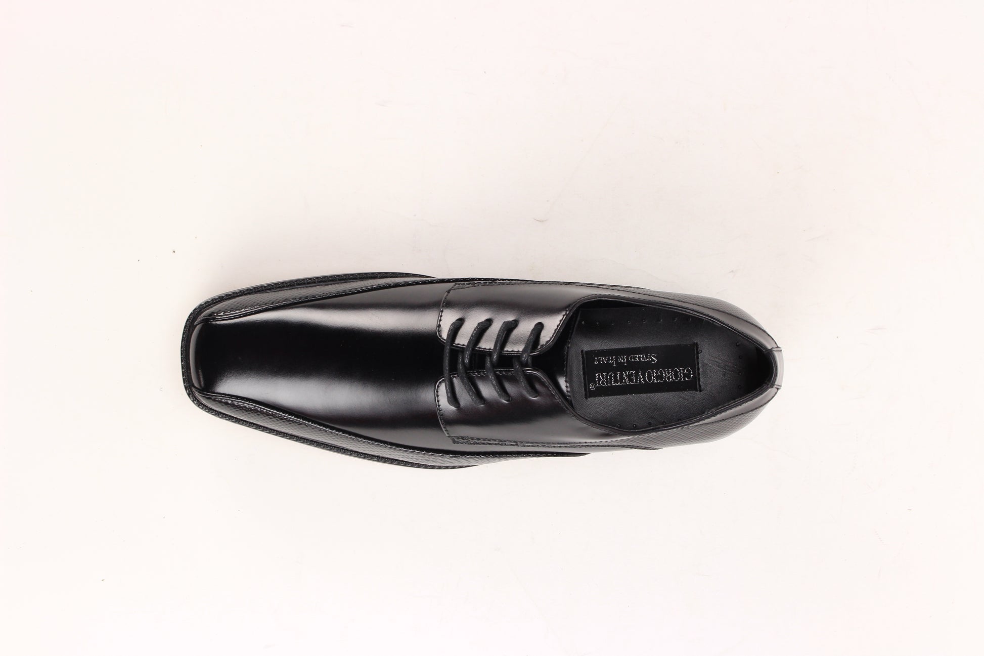 The Giorgio Venturi 7060 Black Leather Shoe features a bike toe, lace-up design, low heel, and embossed textured detailing on the sides and around the sole.
