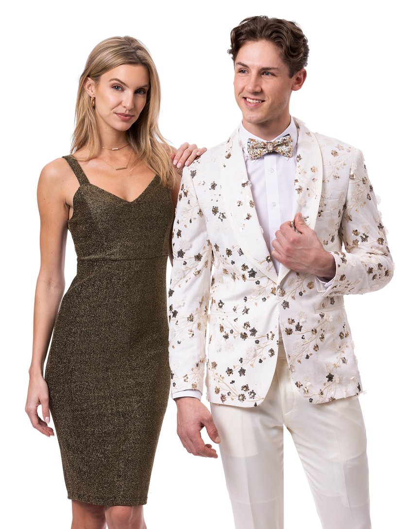 A woman in a sparkly sleeveless dress stands beside a man wearing an EJ SAMUEL floral-patterned blazer, matching pants, and a stylish bow tie from the EJ Samuel Cream Suit JP134 collection.