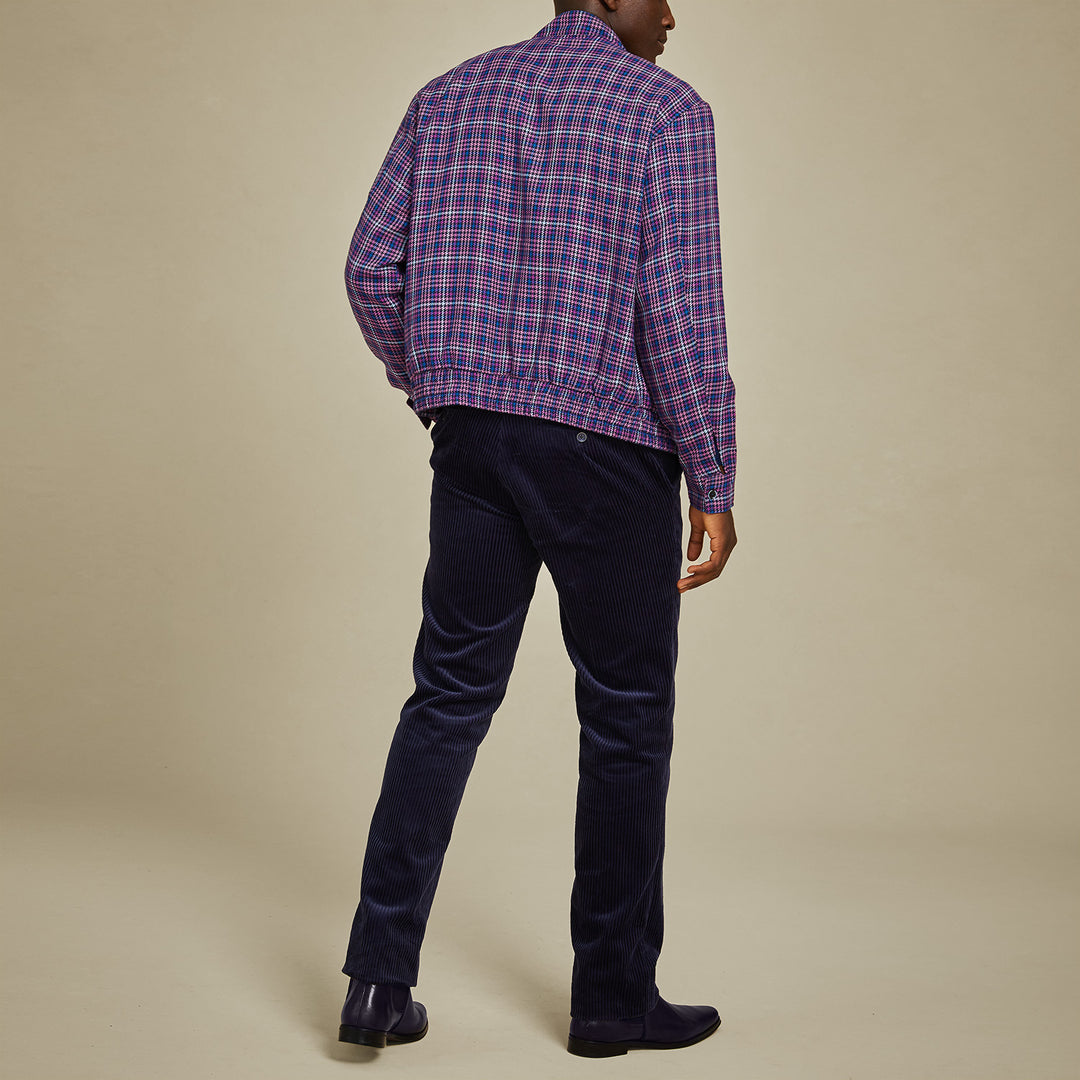 A man stands against a beige background wearing the Inserch Micro Check Full Zip Jacket JS266-126 Purple by Inserch, styled over a light blue sweater and blue pants.