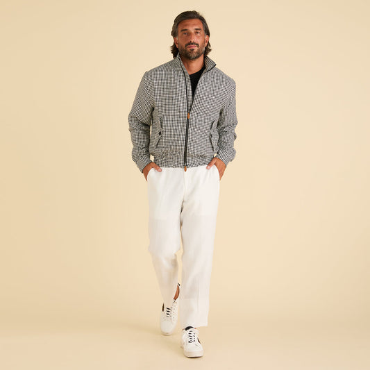 A man stands against a beige background wearing the Inserch Linen Houndstooth Jacket JS269-00041 Black & White by Inserch, paired with white pants, a black shirt, and white sneakers.