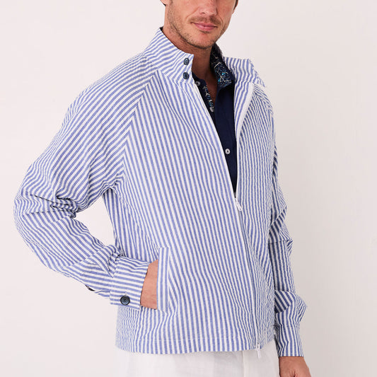 A person sports the Inserch Seersucker Stripe Jacket JS506-00101 in True Blue over a dark shirt, paired stylishly with white shorts and sneakers. They are set against a simple white background.