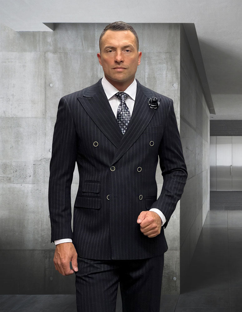 A man in a STATEMENT CLOTHING | KELLY-BLACK suit by Statement Clothing stands in a sleek, minimalist hallway with concrete walls and a polished floor.