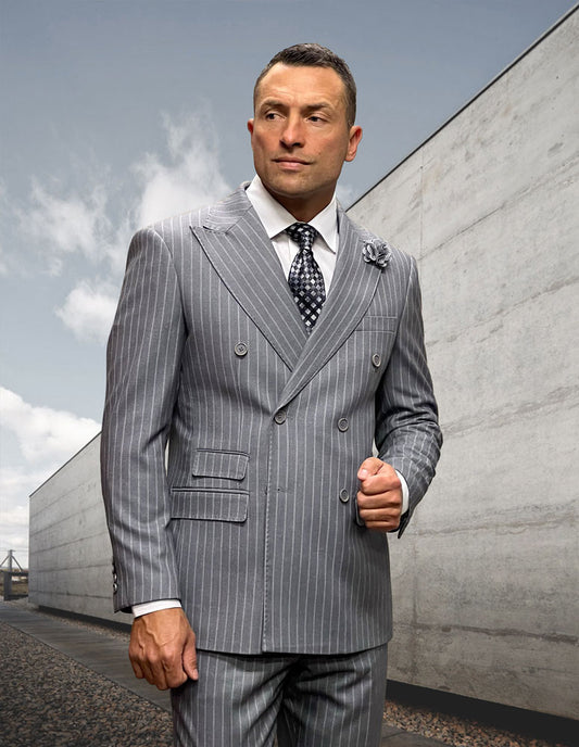 A man in the STATEMENT CLOTHING | KELLY-GREY modern-fit gray Italian wool pinstripe suit by Statement Clothing, paired with a patterned tie, stands outdoors beside a concrete wall under a cloudy sky.