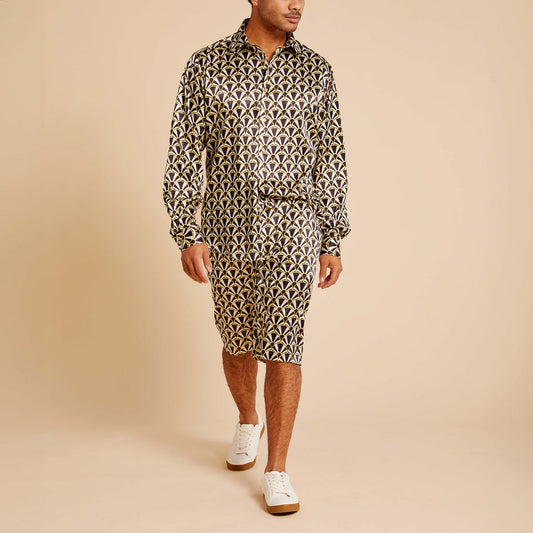 A man wears the Inserch LS Art Nouveau Print Shirt LS051-00001 Black by Inserch with matching shorts and white sneakers, walking against a beige background.
