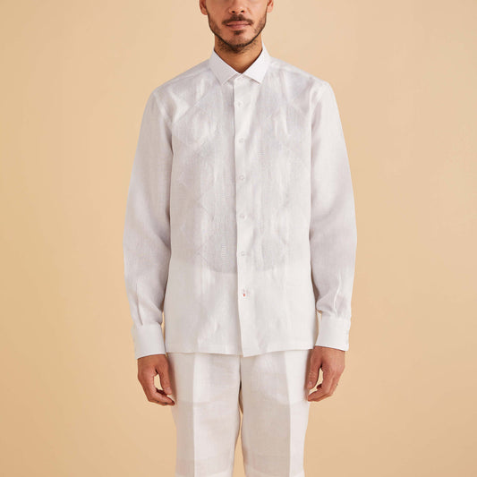 A man stands against a beige background wearing an Inserch LS Linen Embroidered Shirt, style LS126-00002, in white with matching light pants.