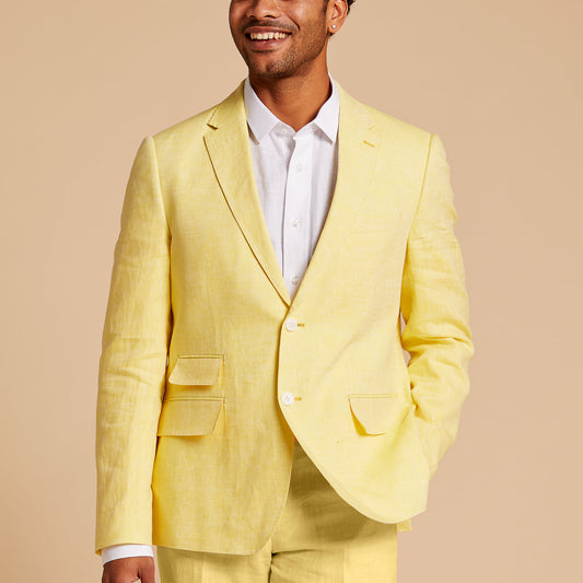 A man stands with one hand in his pocket, smiling against a beige background, dressed in a light yellow suit and wearing the Inserch Linen Long-Sleeve Shirt LS29116-00002 White by Inserch.