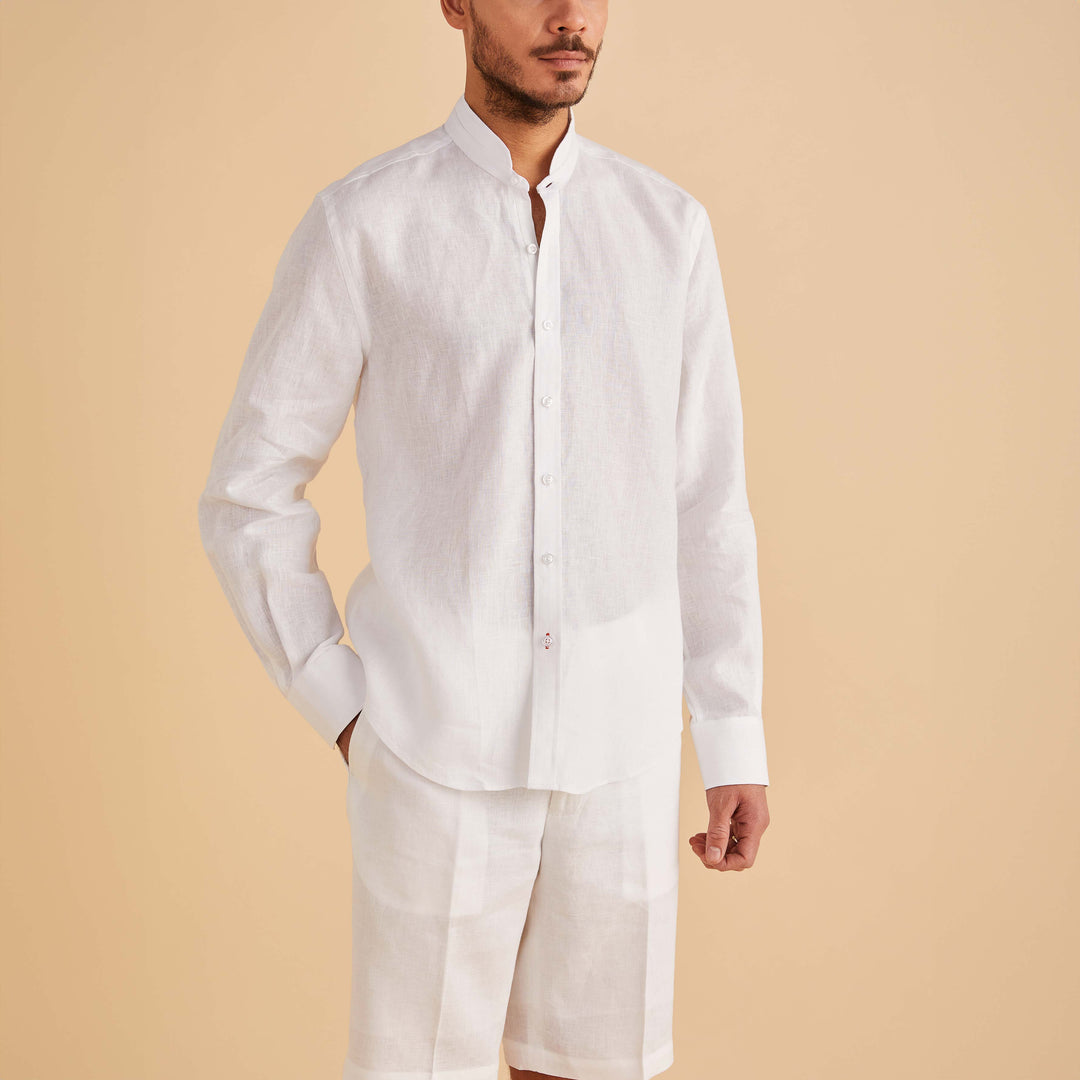A man wearing the Inserch LS Linen Banded Collar Shirt LS716-00002 in white by Inserch, paired with matching white shorts, stands against a beige background.