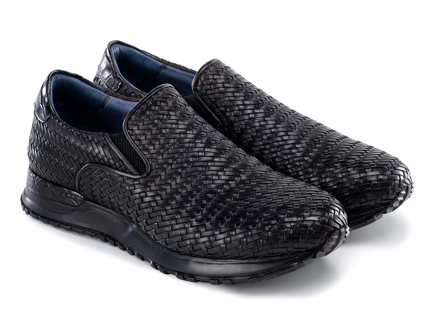 Paul Parkman Men's Black Woven Leather Slip-On Sneakers (LW204BLK) are shown against a white background, featuring stylish textured soles with one shoe resting atop the other.