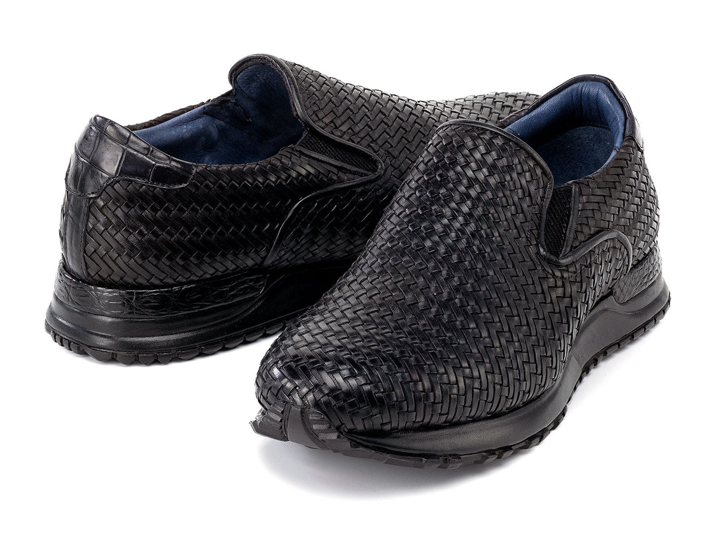 Paul Parkman Men's Black Woven Leather Slip-On Sneakers (LW204BLK) are shown against a white background, featuring stylish textured soles with one shoe resting atop the other.