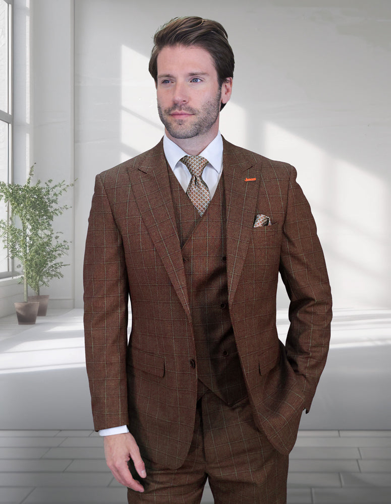 A man in a modern fit STATEMENT CLOTHING | MONTE-COPPER Italian wool suit by Statement Clothing stands indoors near a sunlit window with a potted plant behind him.